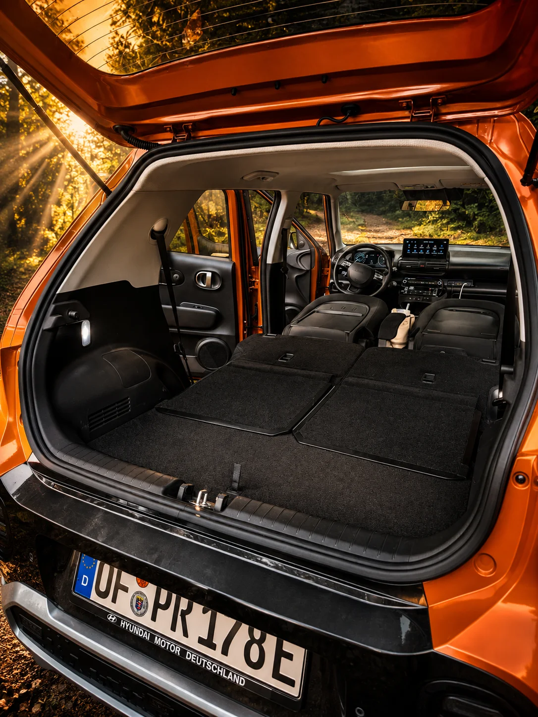 Rear of the orange INSTER with folded rear seats and a flat sleeping area